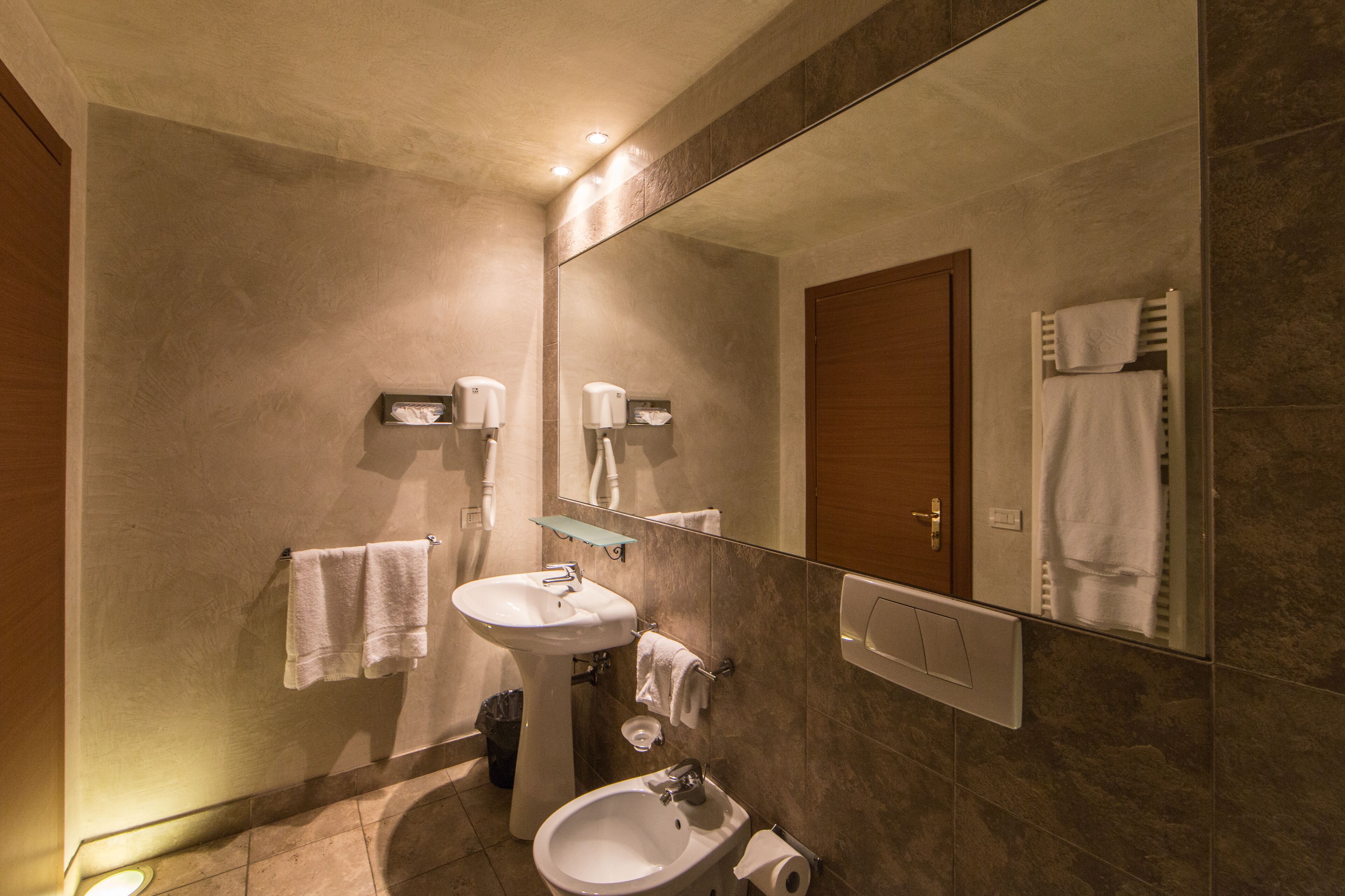 Un bagno con lavandino, specchio, porta asciugamani e porta in legno.