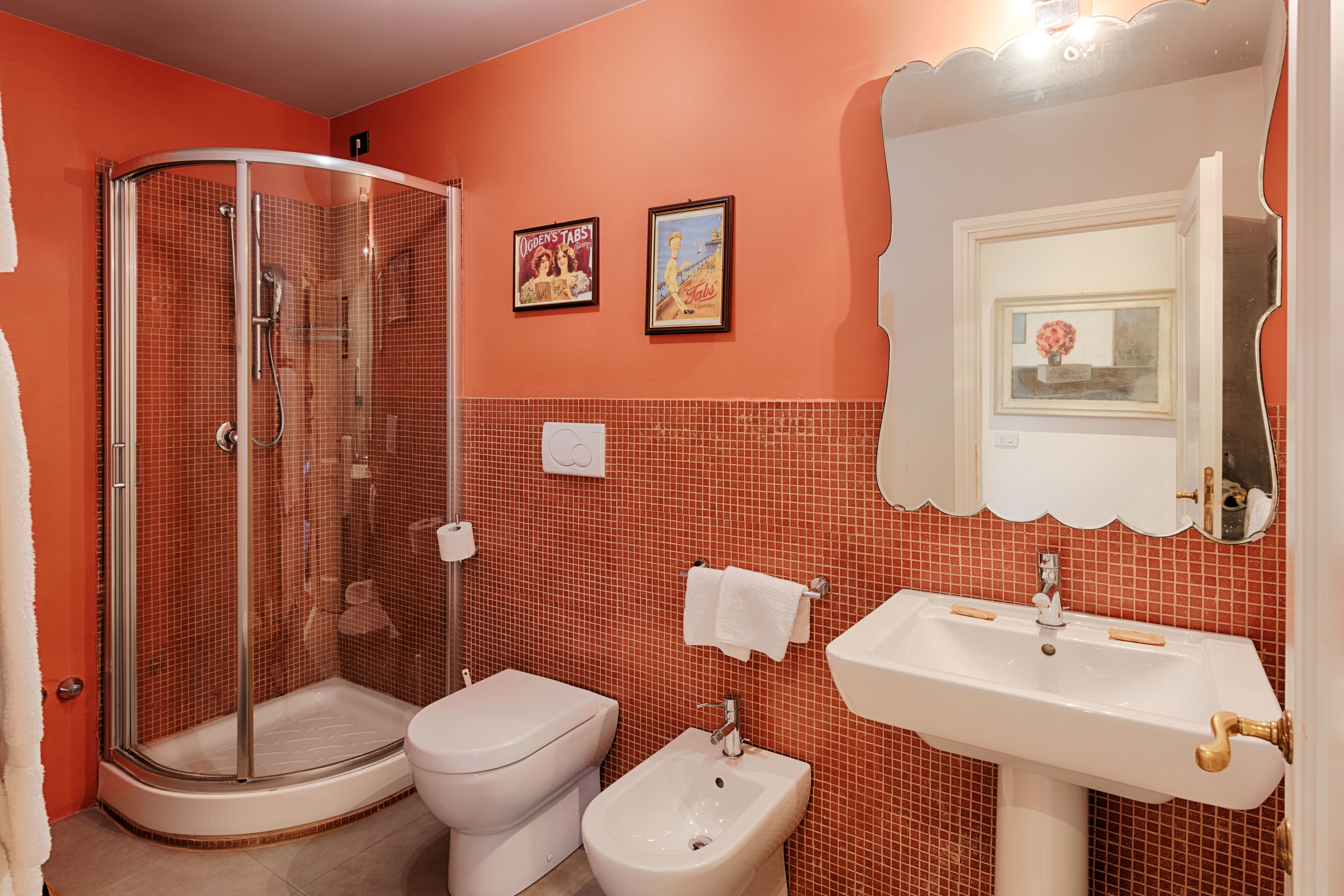 Ein Badezimmer mit einer Duschkabine, Toilette, Bidet und Waschbecken mit Spiegel darüber.