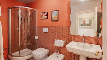 Ein Badezimmer mit einer Duschkabine, Toilette, Bidet und Waschbecken mit Spiegel darüber.