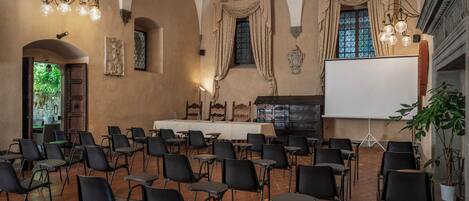 A conference room with black chairs, a whiteboard, and a projector screen.
