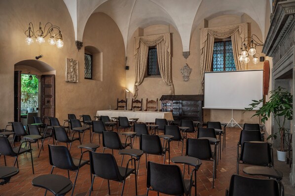 A conference room with black chairs, a whiteboard, and a projector screen.