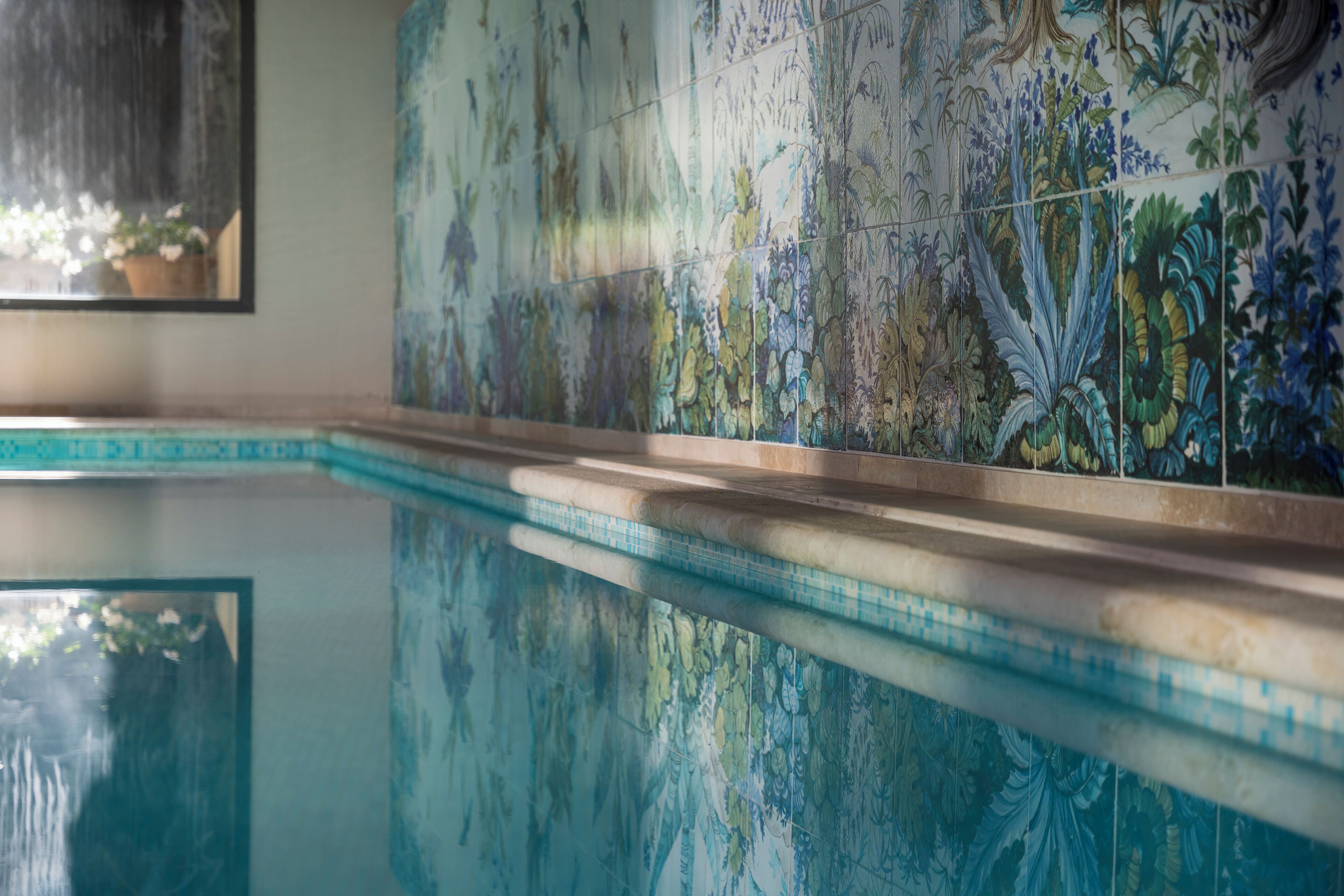 Una piscina con una pared revestida de azulejos con un diseño floral.