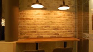 A brick wall with two hanging lamps, a wooden table, and two chairs. - Hotel Castillo (Palma del Rio)