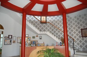 A reception area with a staircase, framed certificates, and a reception desk. - Hotel Castillo (Palma del Rio)
