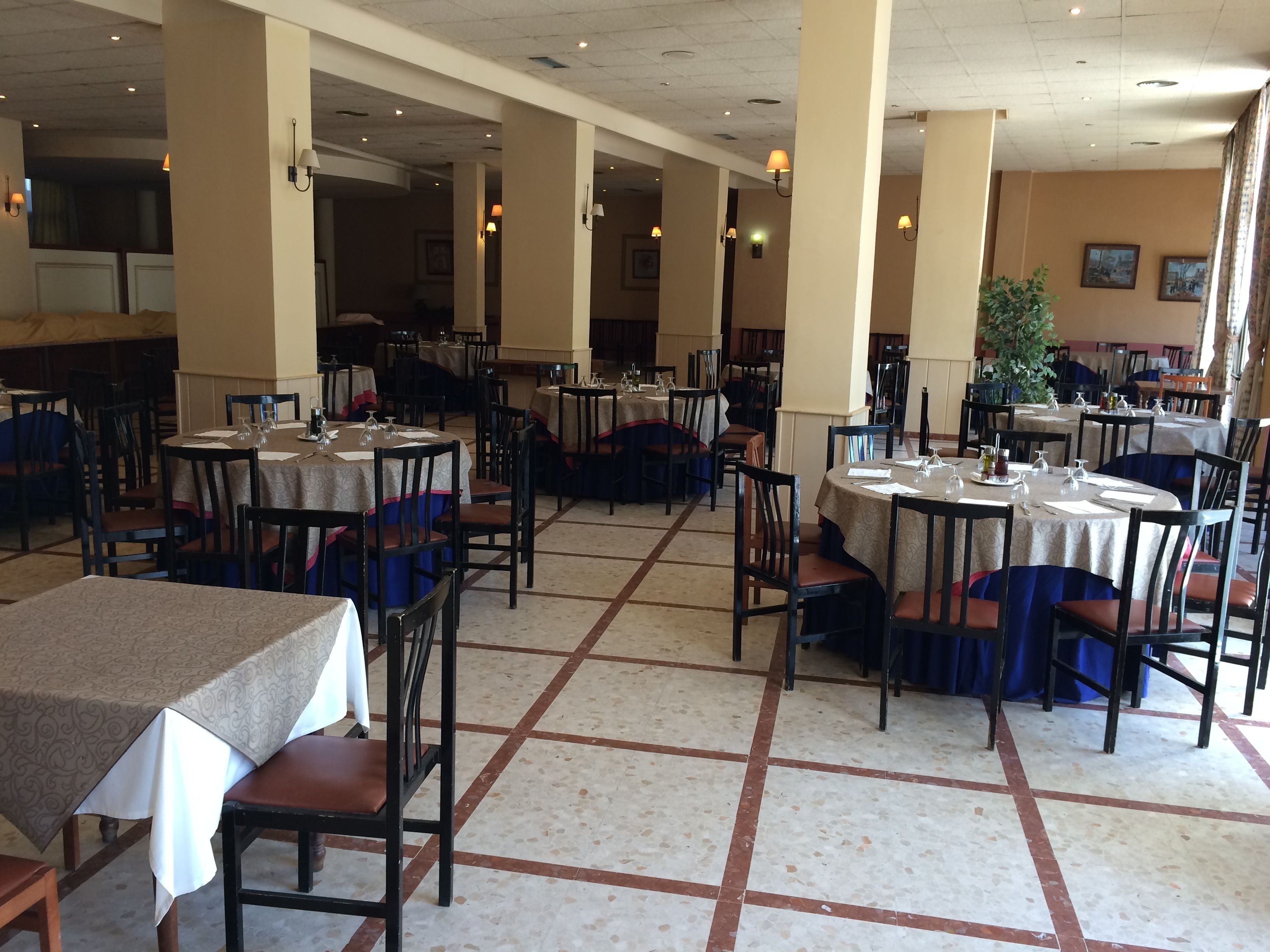 Un restaurant spacieux, doté de nombreuses tables et chaises disposées selon un plan en forme de grille.