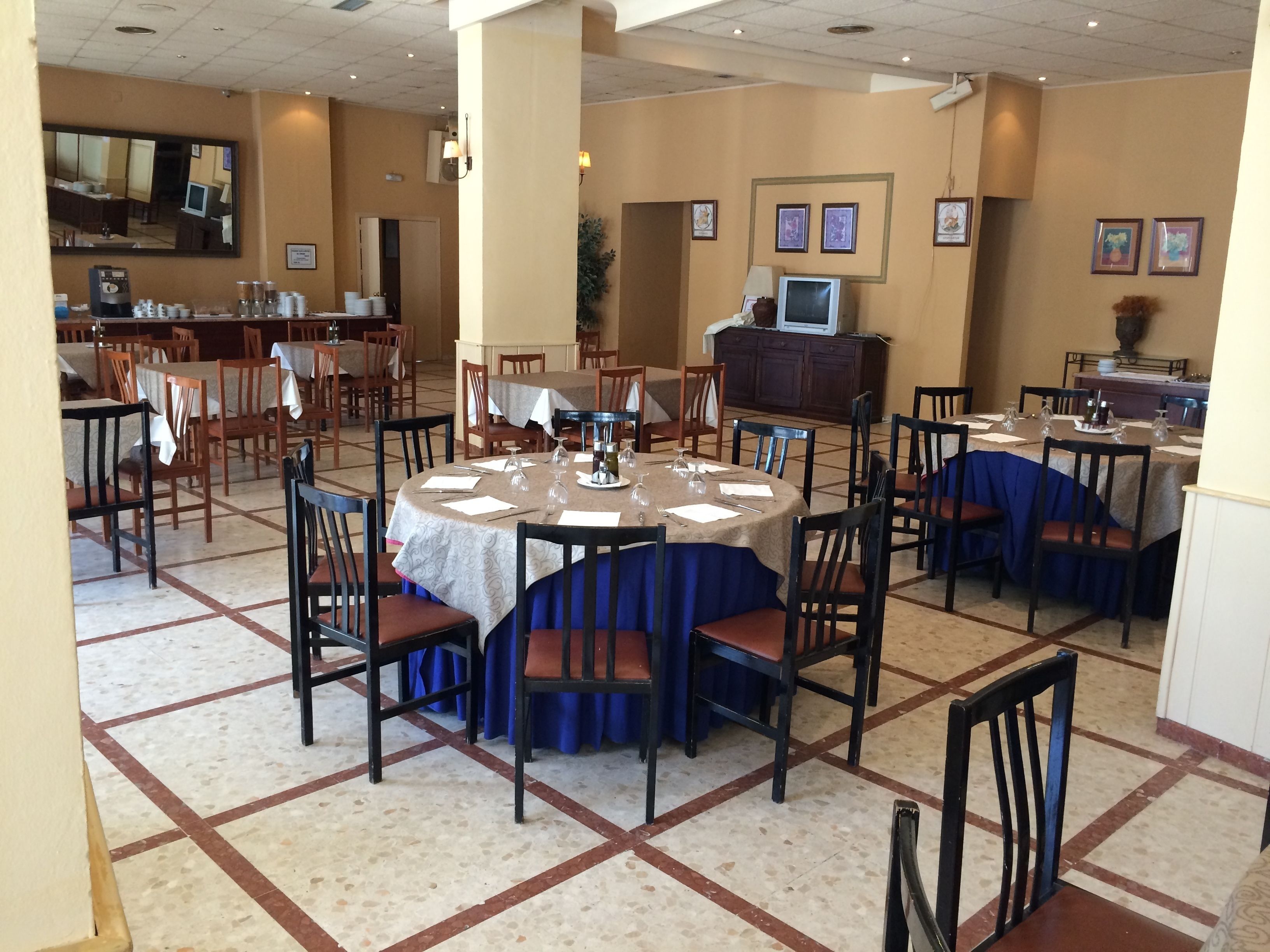 Un comedor con mesas redondas, sillas y una pantalla de televisión.