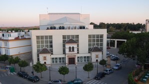 A modern building with a central entrance, large windows, and a surrounding parking area. - Hotel Castillo (Palma del Rio)