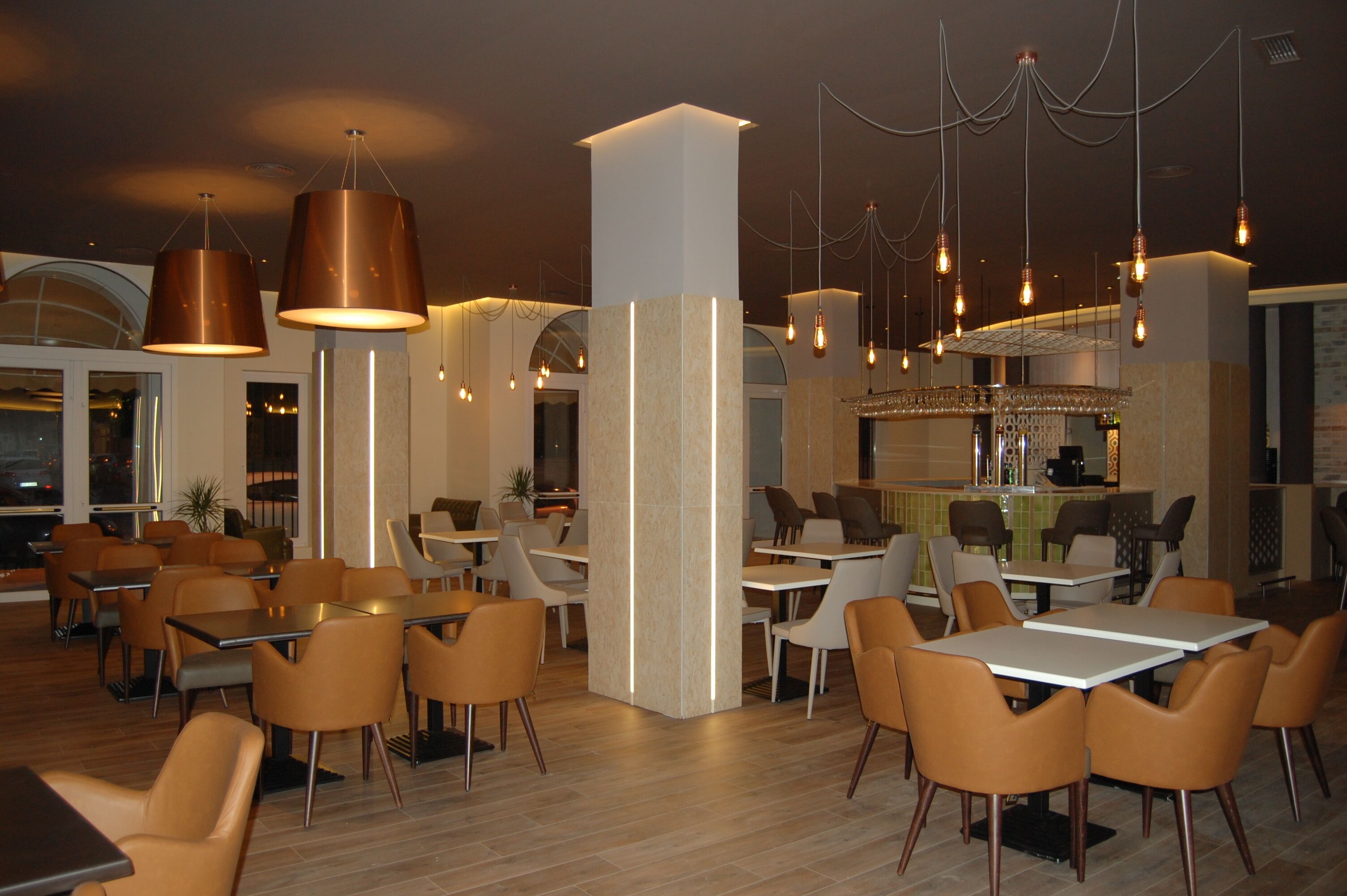 Een modern restaurant met verschillende zithoeken, waaronder tafels en stoelen, en een bar.