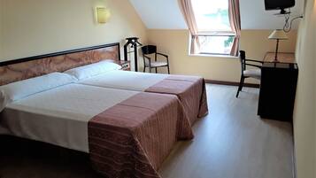 Hotelkamer met twee bedden, een bureau, een stoel, een televisietoestel en een raam met gordijnen.