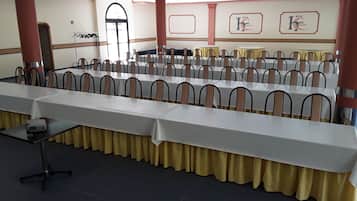 A banquet hall with long tables, chairs, and a stage area.