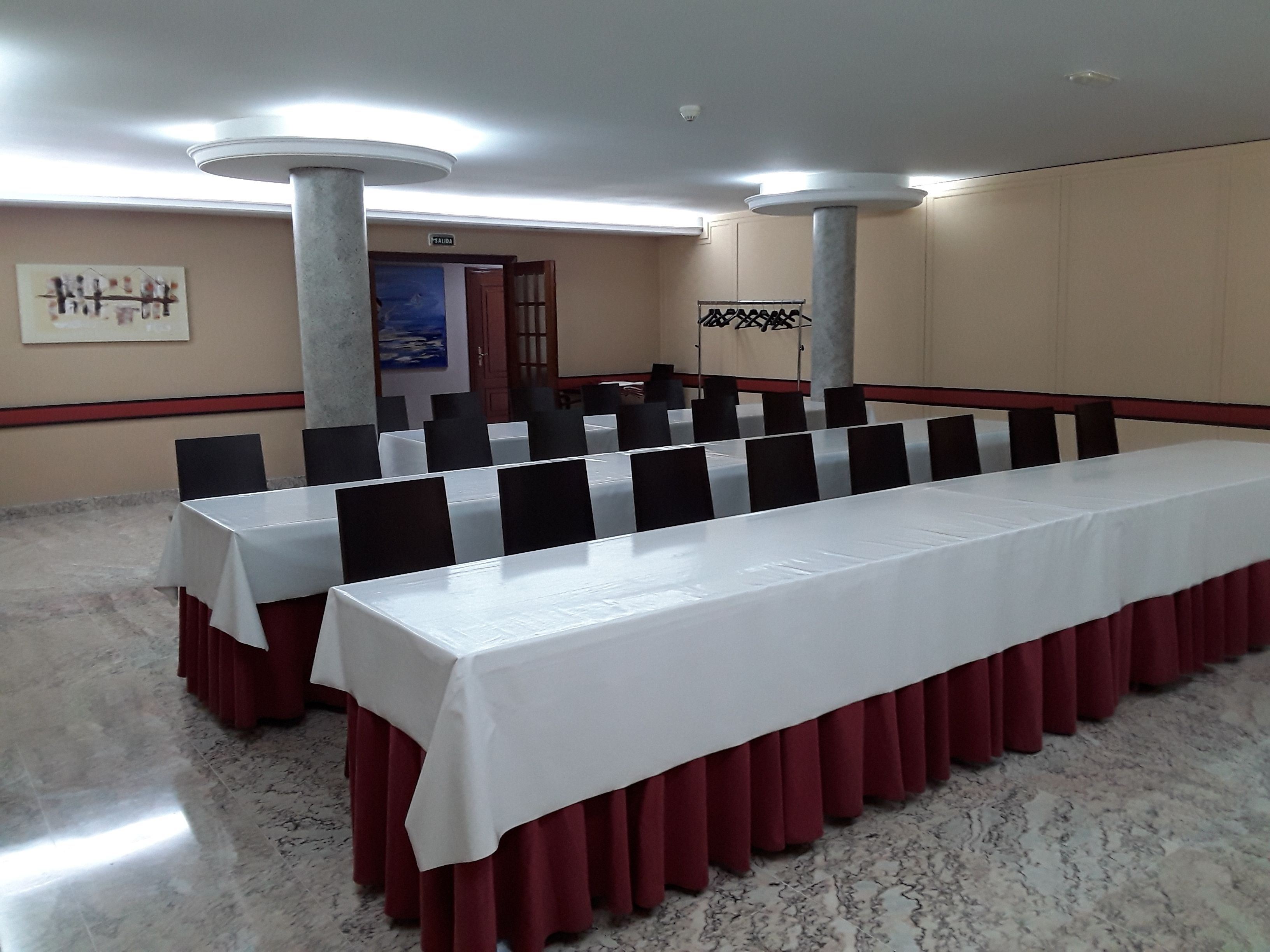 A conference room with a long table, black chairs, and a white tablecloth.