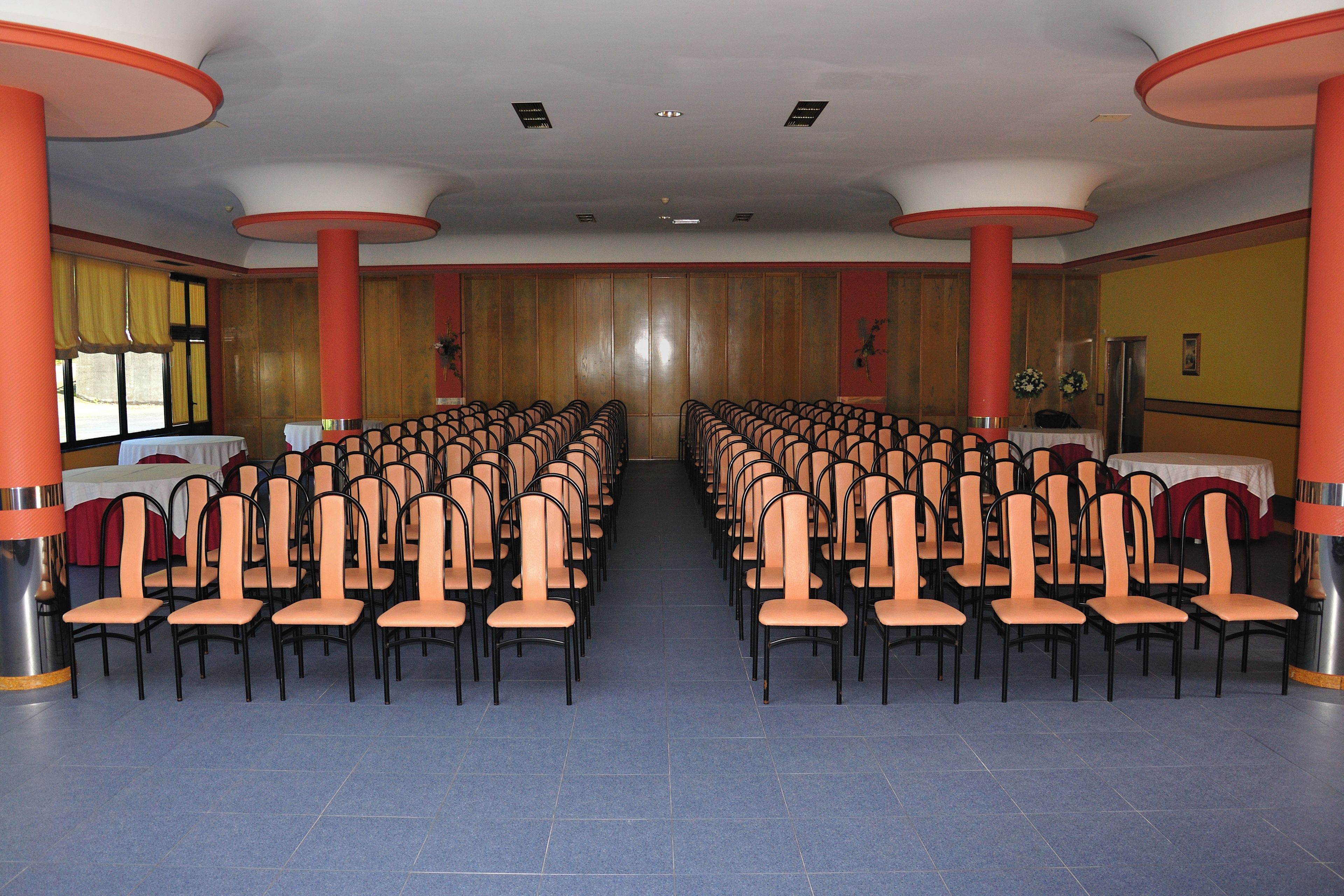 Een vergaderzaal met rijen stoelen, een podium en een spreekgestalte.
