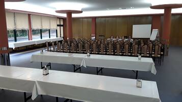 Un salón de conferencias con varias mesas y sillas, una pizarra y vistas amplias a través de grandes ventanales.
