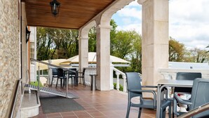 A covered outdoor patio with a tiled floor, stone columns, and outdoor furniture. - Hotel Castro (Santiago de Compostela)