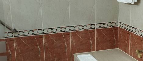 A bathroom with a shower, a toilet, and a towel rack.