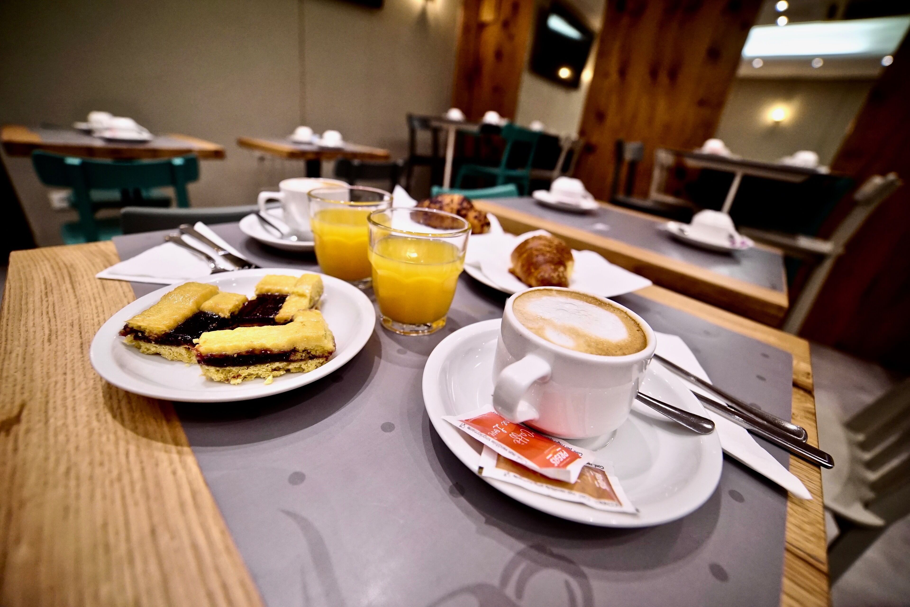 Una colazione con un piatto di pasticcini, una tazza di caffè e un bicchiere di succo d'arancia su un tavolo.