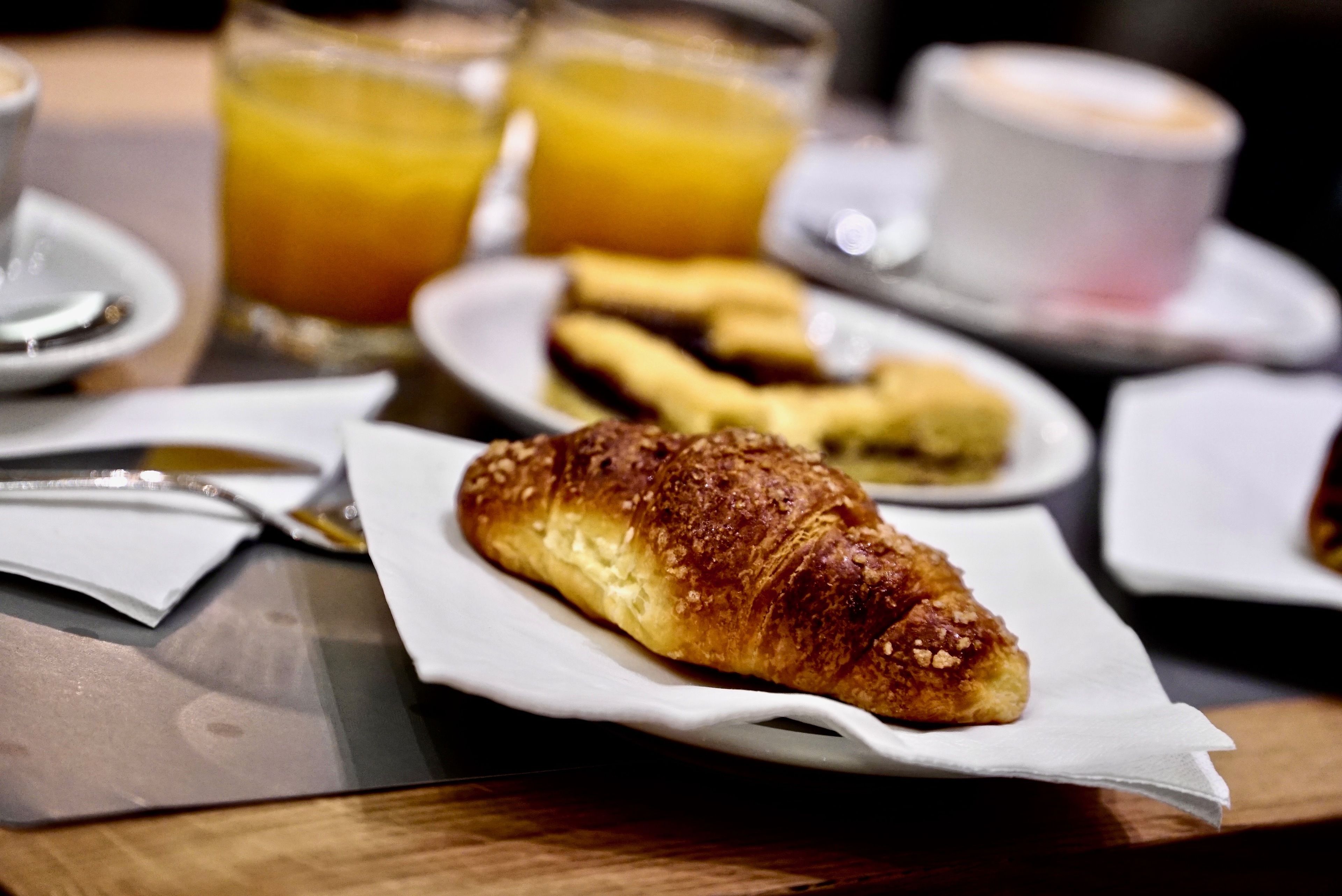 A breakfast setting with croissants, juice, and coffee.