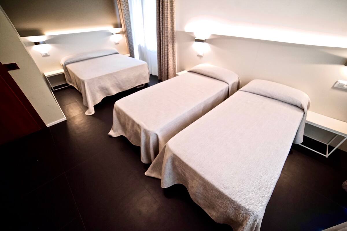 A hotel room with two single beds, a small desk, and a nightstand.