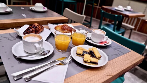 A breakfast setting with croissants, juice, coffee, and a plate of pastries on a table. - Hotel Centrale (Mestre)