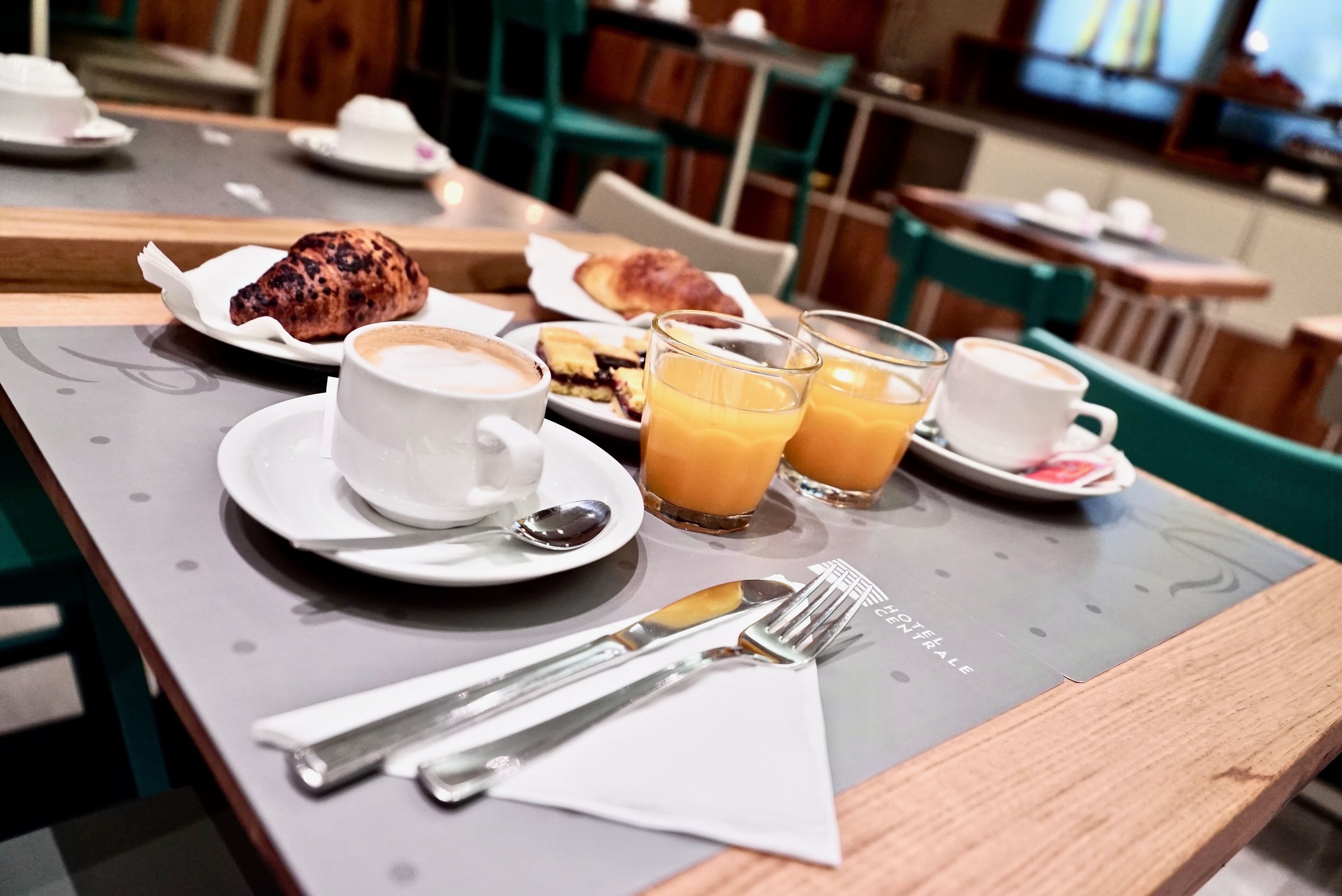 A breakfast setting with croissants, coffee, and orange juice on a table.