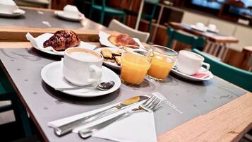 A breakfast setting with croissants, coffee, and orange juice on a table.