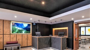 A modern reception area with a large TV screen, a wooden bench, and a reception desk. - Hotel Centrale (Mestre)