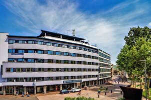 Un hotel moderno con una facciata curvilinea, diversi piani e un ingresso ben visibile.