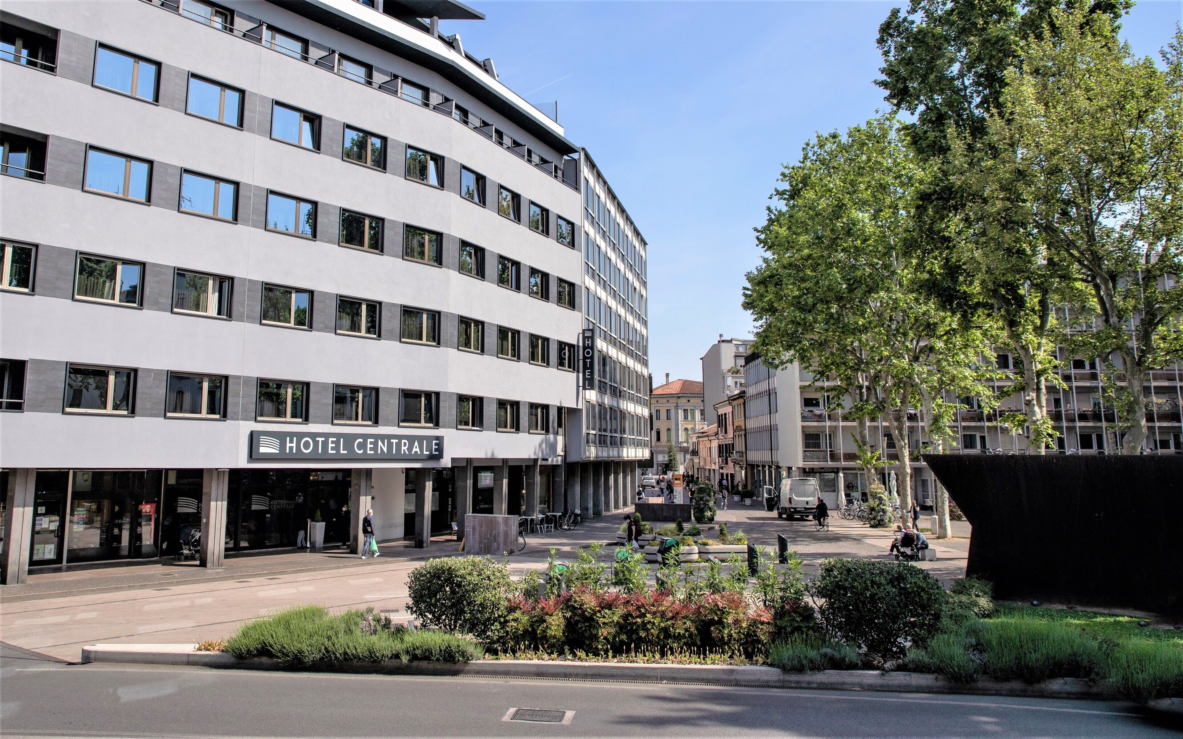 A modern hotel building with a curved facade, multiple windows, and a sign reading "HOTEL CENTRALE".