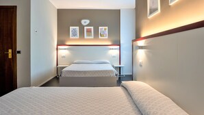A hotel room with a large bed, bedside tables, a nightstand, and a wall-mounted light fixture. - Hotel Centrale (Mestre)