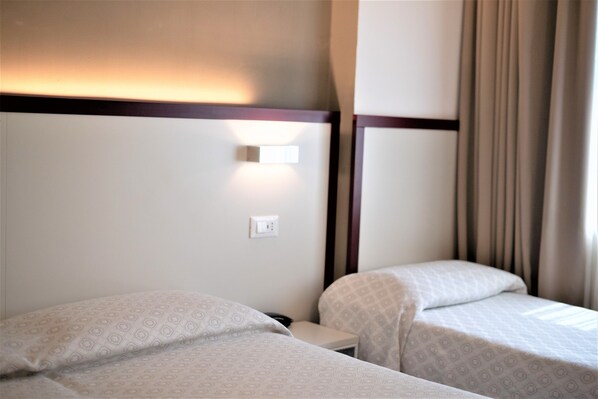 A hotel room with two single beds, a nightstand, a wall-mounted light, and a power outlet. - Hotel Centrale (Mestre)