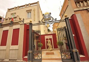 A hotel entrance with a statue, a sign reading "Aurelius Hotel," and a decorative gate. - Aurelius Art Gallery Hotel (Rome)