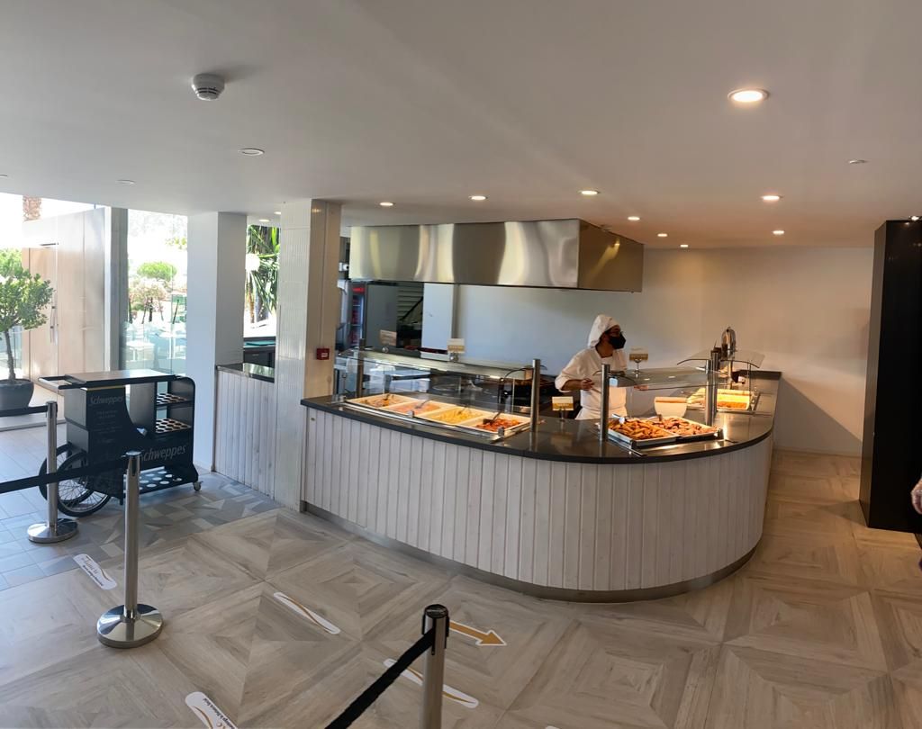 A buffet area with a counter, food display, and a person serving.