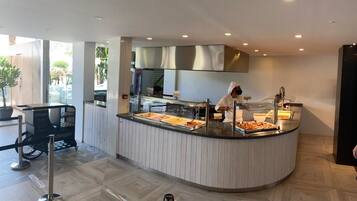 A buffet area with a counter, food display, and a person serving.