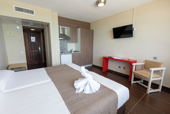 A hotel room with a bed, a desk, a chair, a TV, and a kitchenette. - Flamero (Almonte)