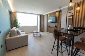 A modern living room with a sofa, a small round table, and a dining area with chairs.