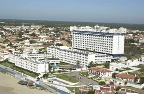 A large hotel complex with multiple buildings, a beach area, and a clear view of the surrounding cityscape. - Flamero (Almonte)