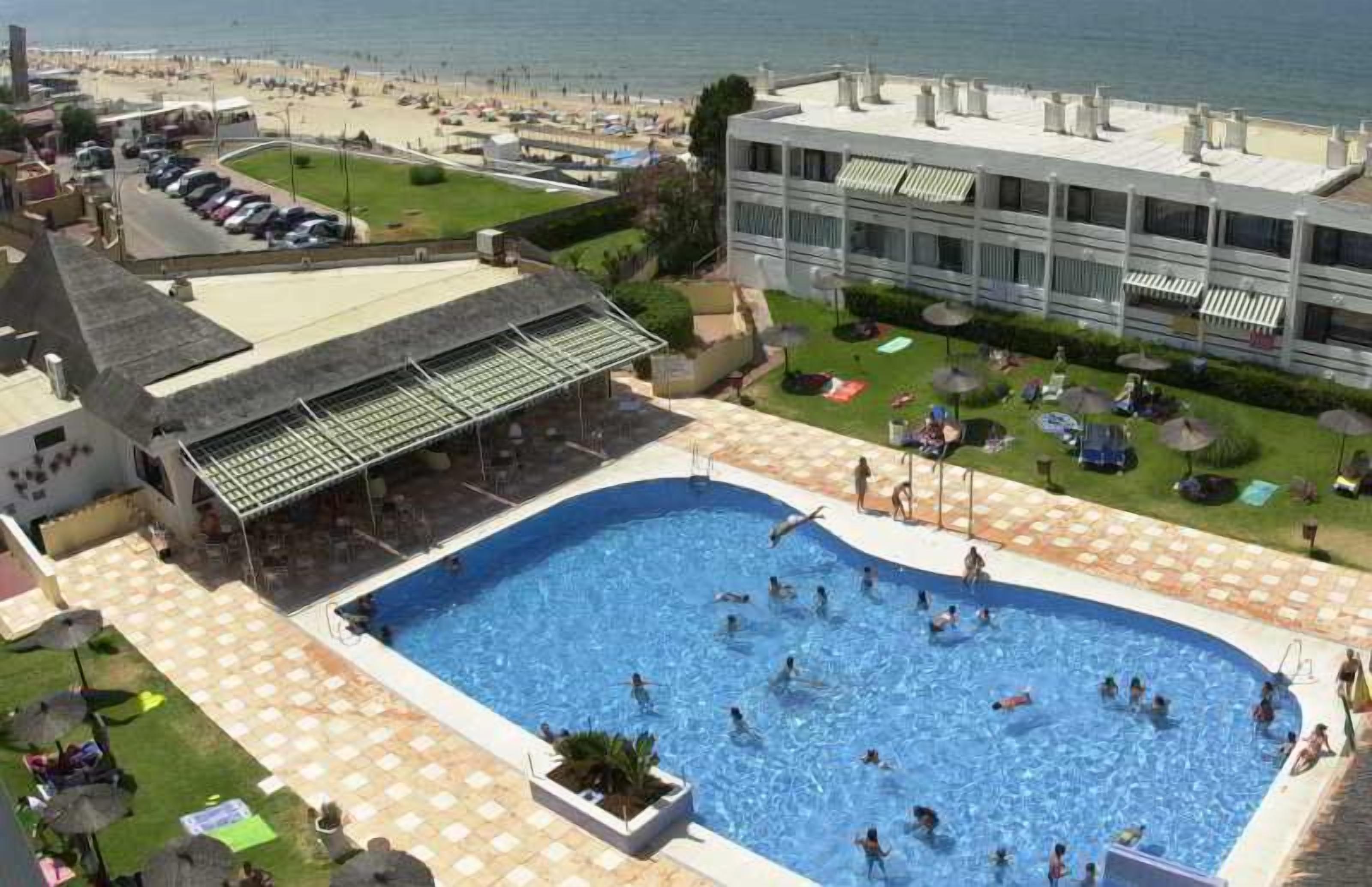 Hotel amb una gran piscina, zones d'estar a l'aire lliure i vistes a la platja.