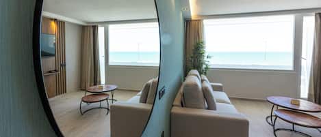 Habitación de hotel moderna con un espejo grande, un sofá, una mesita y vistas al mar.