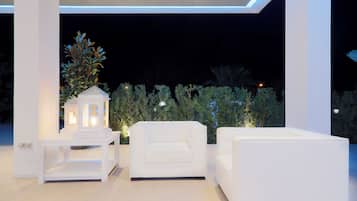 A modern outdoor seating area with white furniture and a decorative tree.