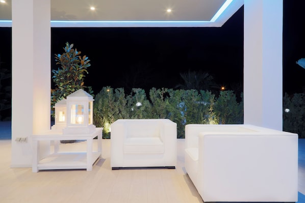A modern outdoor seating area with white furniture and a decorative tree. - Flamero (Almonte)