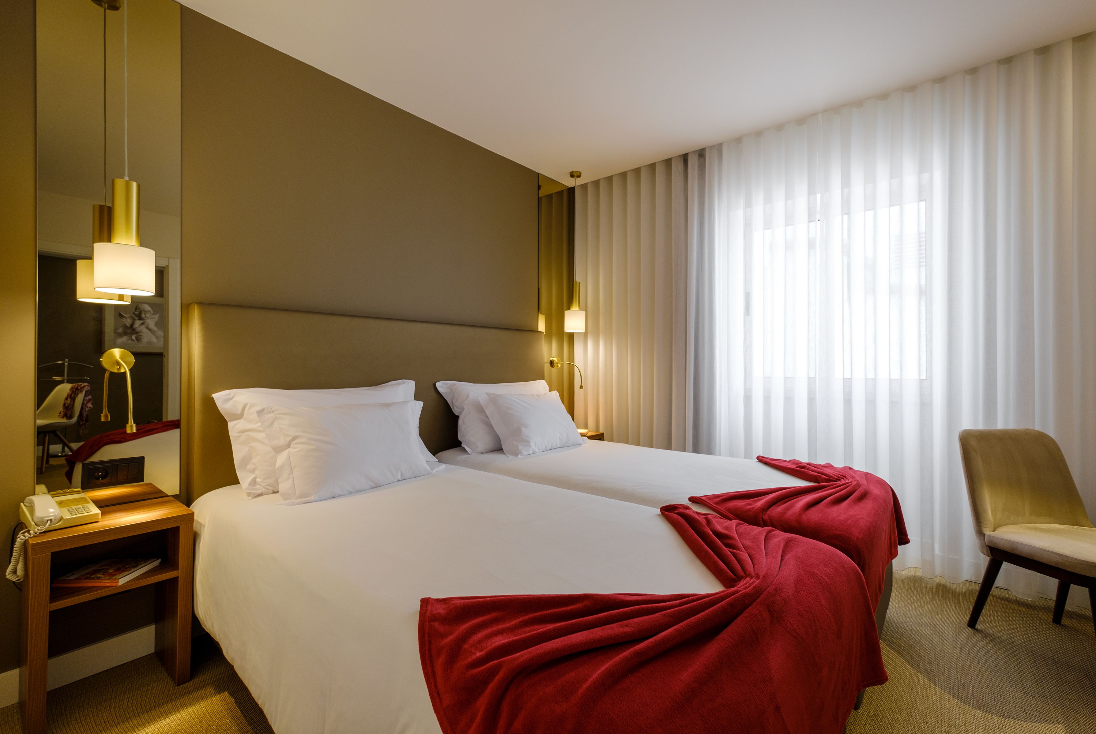 A hotel room with two beds, a desk with a telephone, and a chair.