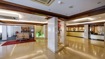 A spacious lobby with a reception desk, seating area, and a decorative plant display.