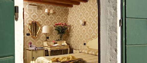 Un dormitorio con cama, mesita de noche, lámpara y espejo.