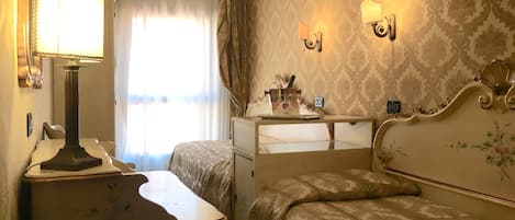 Een hotelkamer met een bed, nachtkastje met lamp, dressoir en spiegel.