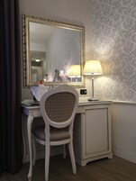 Une chambre d’hôtel équipée d’un coin coiffeuse comprenant un miroir, une lampe et une chaise.