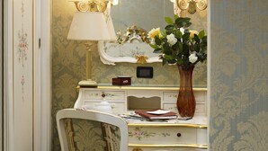 Quarto clássico e elegantemente decorado, com uma penteadeira antiga, espelho ornamentado e um vaso de flores.