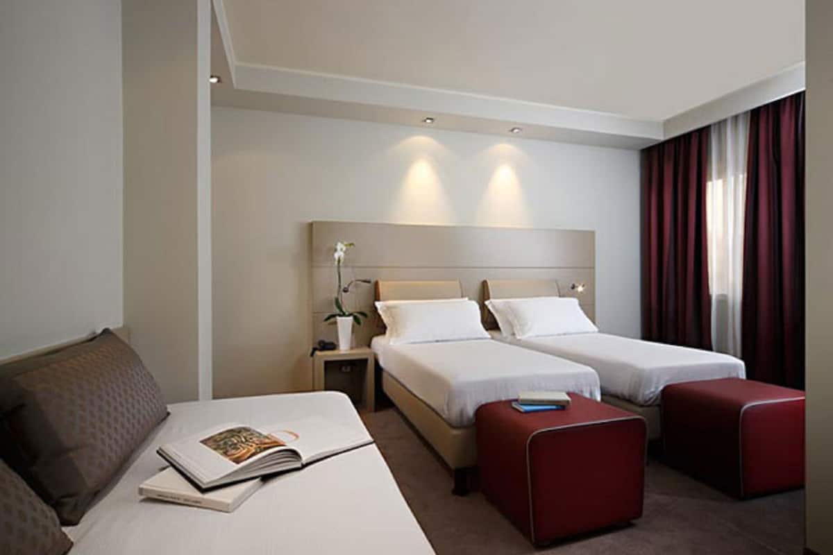 Une chambre d’hôtel avec deux lits, un canapé et un coin lecture.