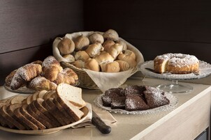 Una varietà di prodotti da forno su un bancone, tra cui pane, panini e dolci.
