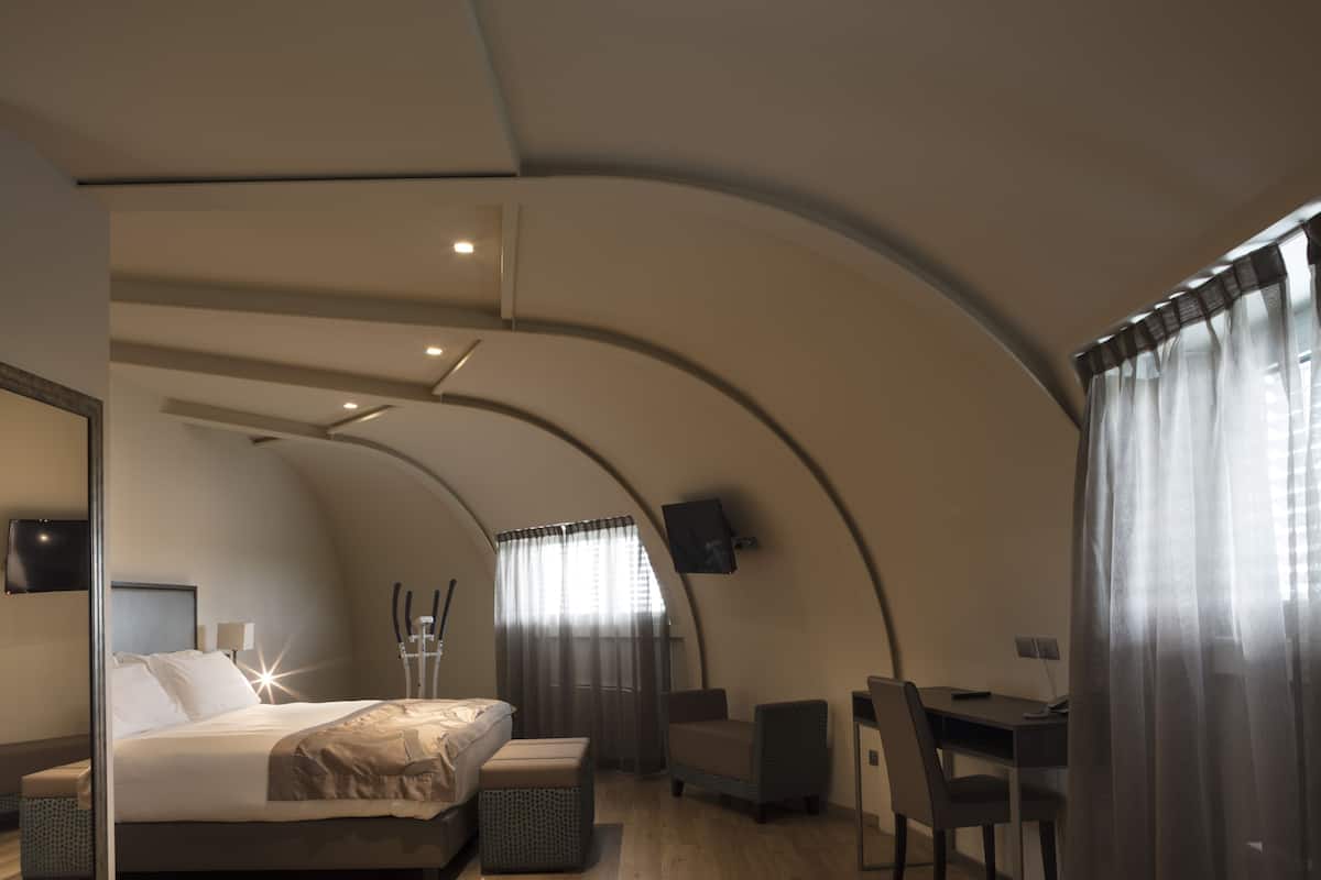 Une chambre à coucher moderne avec un plafond incurvé, un lit, un bureau et une chaise.