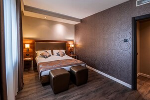 Camera d'albergo moderna con un letto grande, due comodini con lampade, una testiera e un muro decorato.